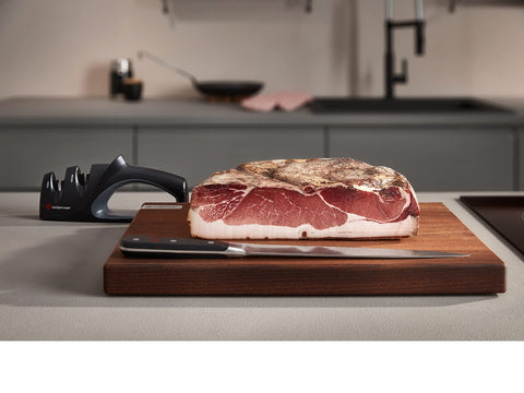 Wüsthof sharpener next to chef knife showing compact size and portability