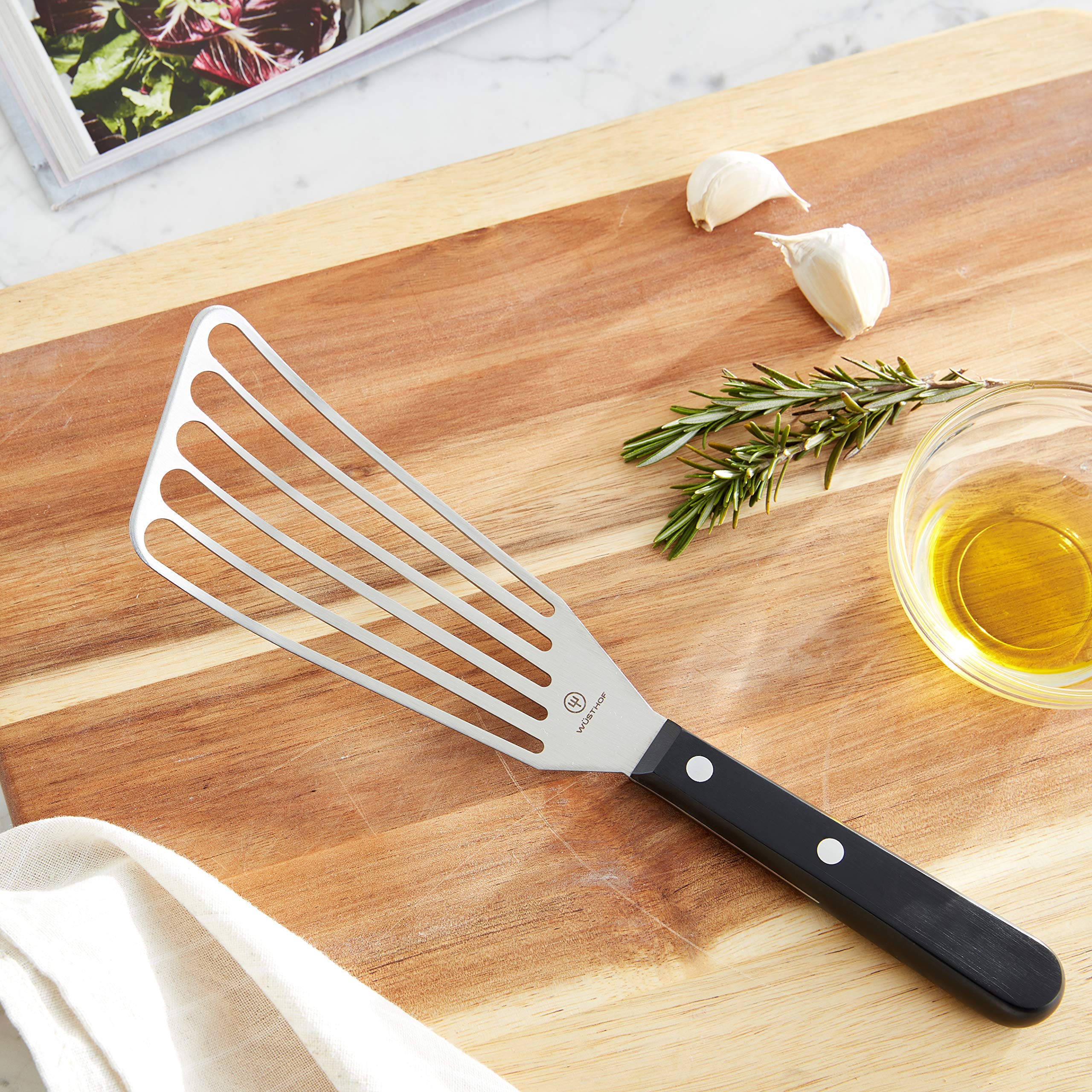 Wüsthof spatula blade close-up highlighting thin stainless-steel edge and slots for easy sliding