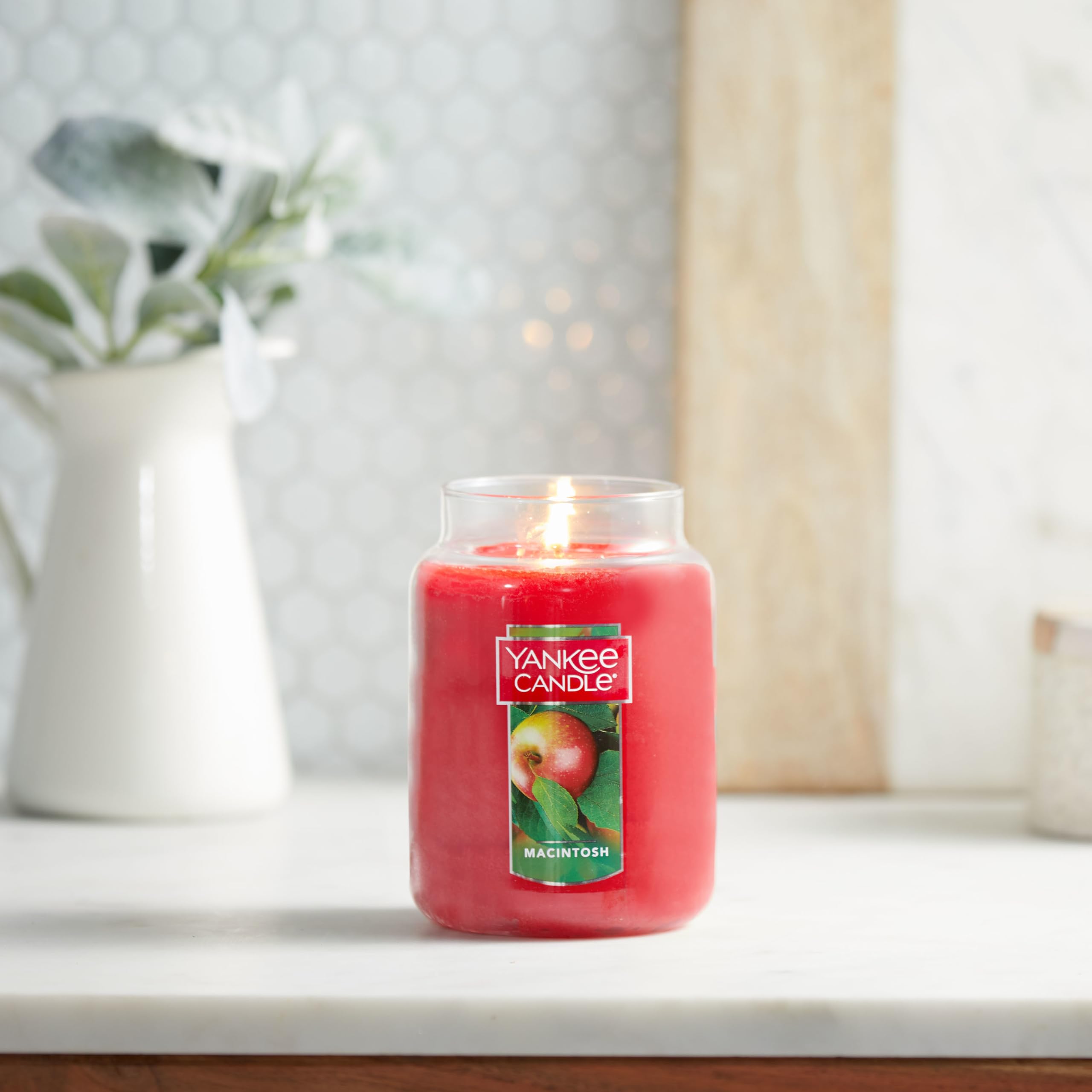 Yankee Candle Macintosh held in hand to show 22-ounce scale and long-lasting burn
