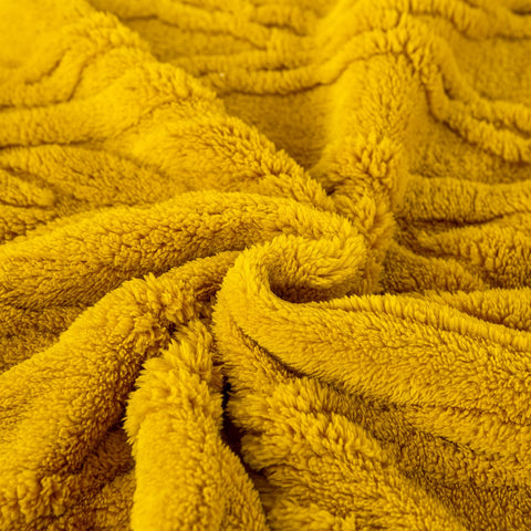 YUSOKI throw styled on bed showing room-enhancing warmth and color
